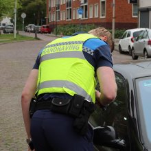 Boa op de rug gezien, hij kijkt in een autoraam naar aanleiding van een melding.