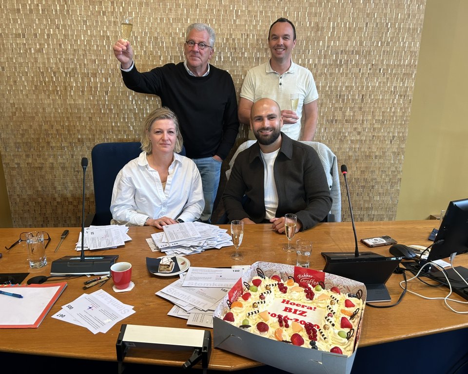 Toostmoment nieuwe BIZ, op de voorgrond een taart met 'Hoera BIZ'