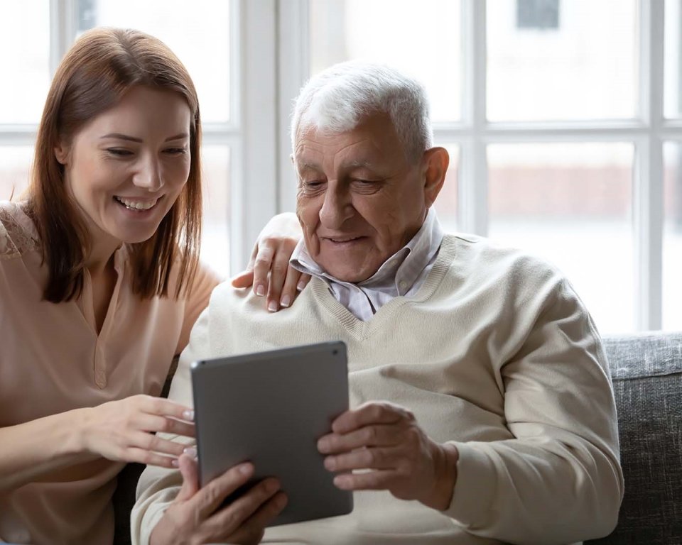 Oude man met iPad en jong meisje als hulp  