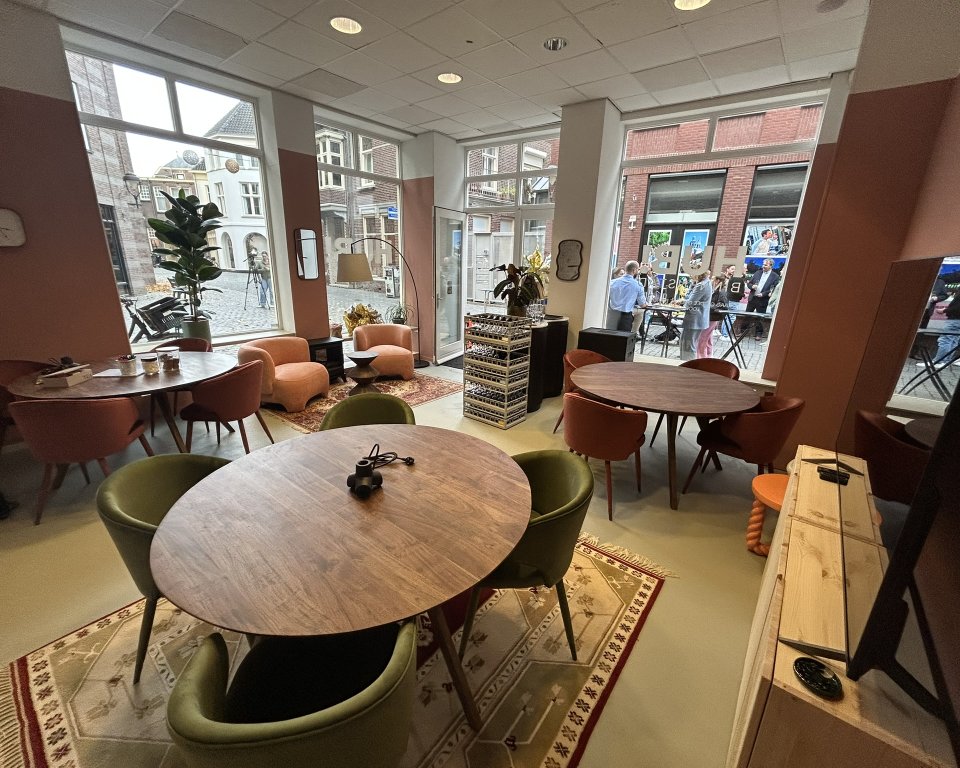 Binnen ruimte met 3 ronde tafels met stoelen. 