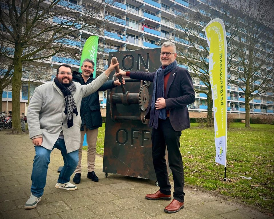 Wethouders van Aken en Verroen en dhr. van Loon van Stadlander staan voor flat met een schakelaar