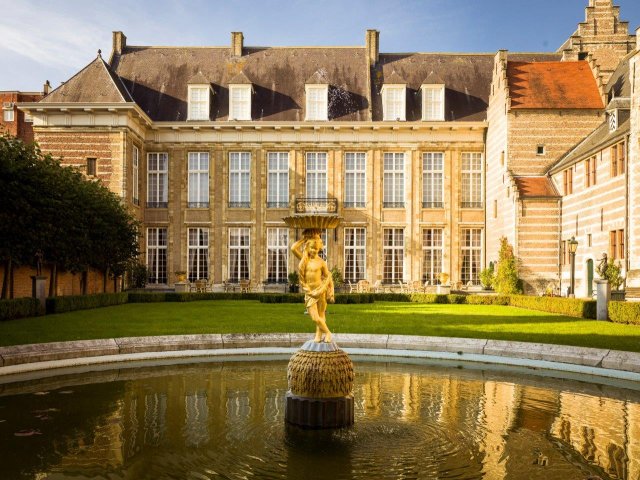 De vijver van het Markiezenhof, met in het midden een gouden beeld en op de achtergrond een deel van het gebouw.