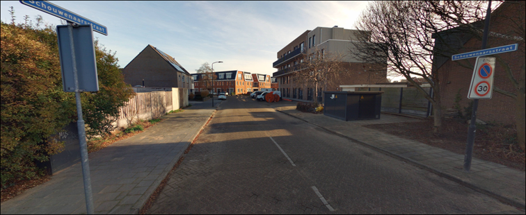 Een straat met een weg van klinkers en stoepen aan beide kanten. Rechts staan gebouwen en op de voorgrond staat een straatnaambord met de tekst ‘Schouwenaarsstraat’.