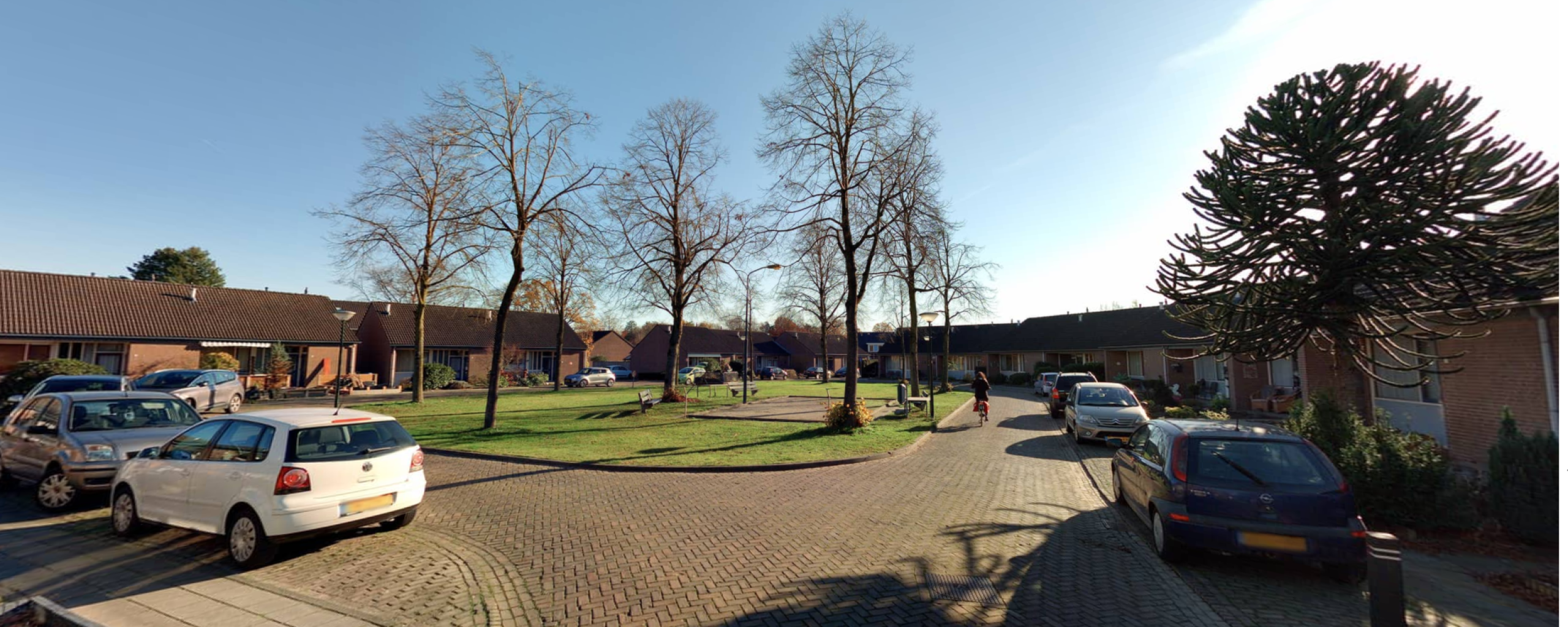 Straatoverzichtsfoto met een groen plein en enkele auto's