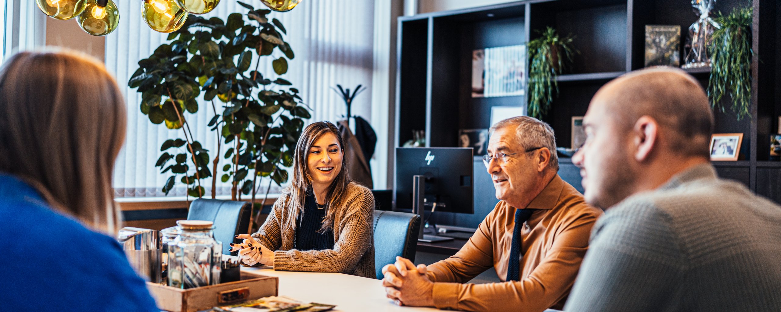 Vier collega's zitten aan tafel te praten