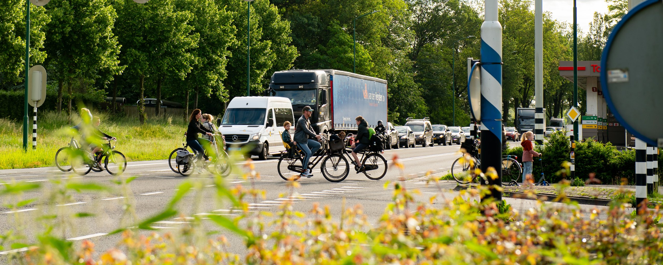 n284, waar fietsers een kruispunt oversteken en er auto's staan te wachten voor een verkeerslicht