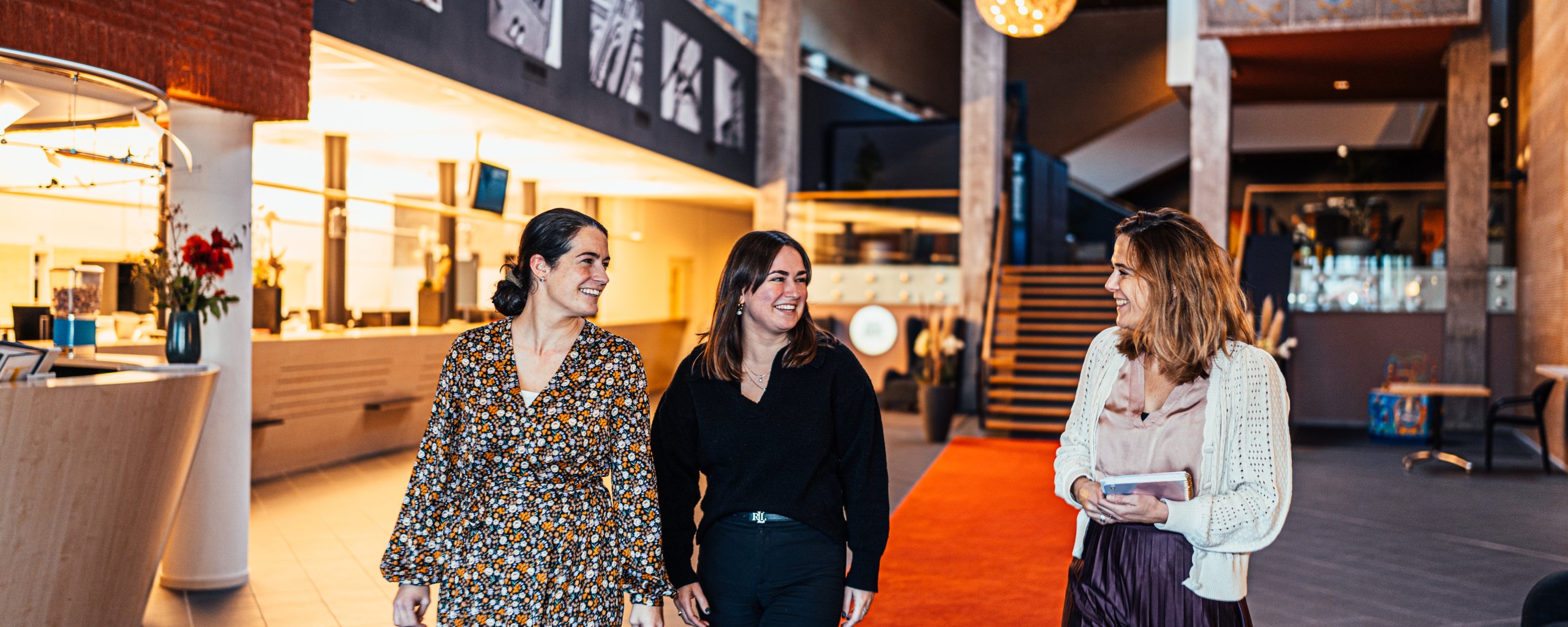 Drie collega's wandelen door het gemeentehuis en zijn in gesprek met elkaar