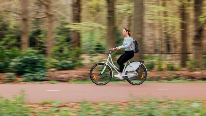 jonge vrouw fietst op een fietspad door het bos