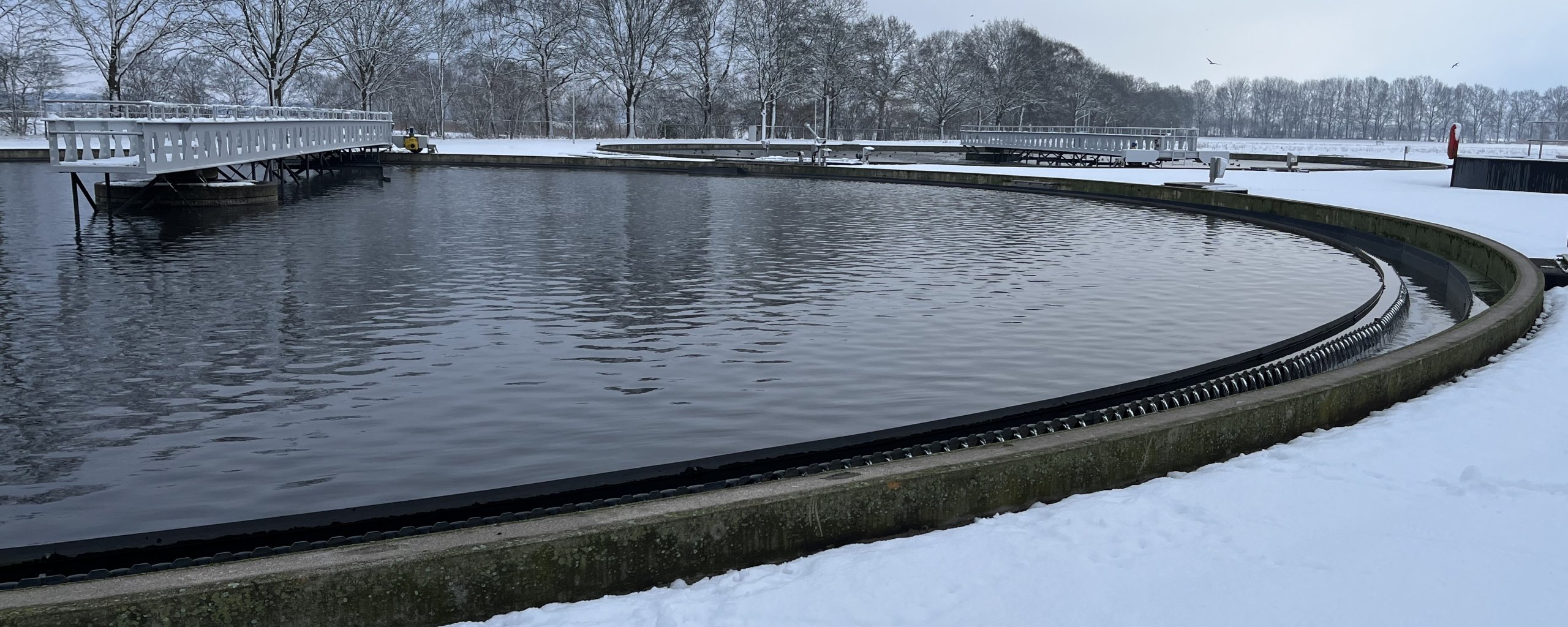 Nabezinktank met sneeuw op de rioolwaterzuivering