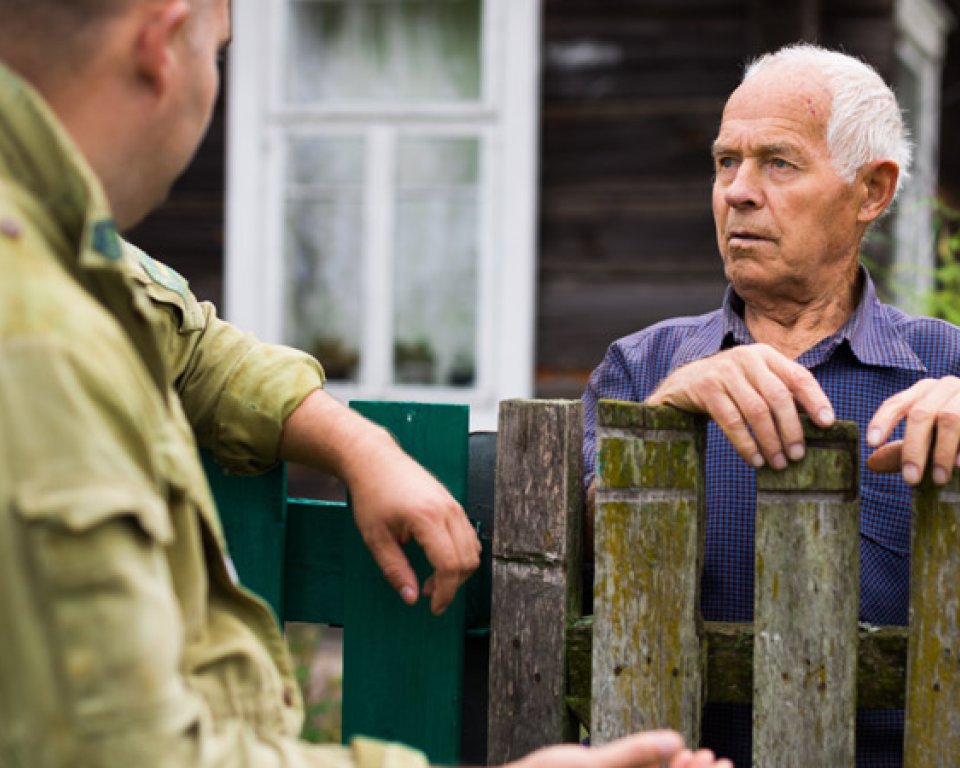 Twee mannen, elk aan een kant van het hek tussen hun tuinen