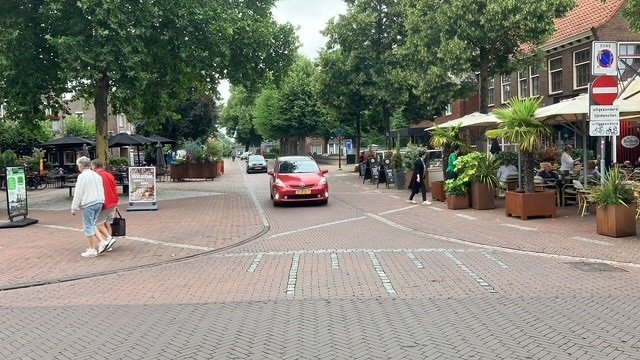 Straat in centrum van Zelhem met terras, wandelaars en auto's