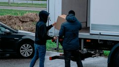 Twee mannen in donkere kleding laden dozen in een vrachtwagen