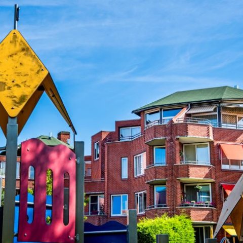 Appartementengebouw De Bergen met speeltoestellen op de voorgrond