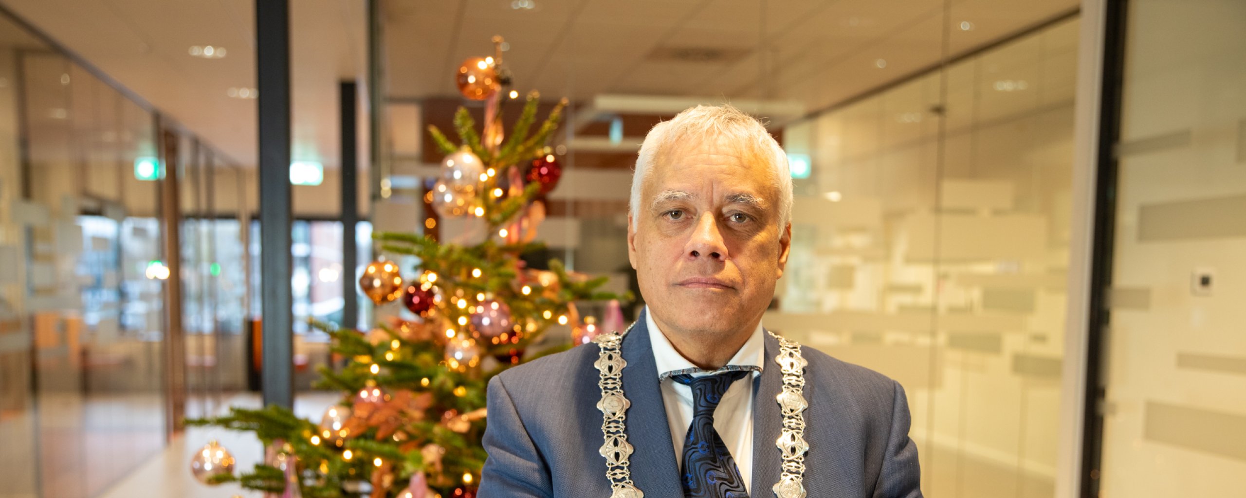 Burgemeester Joost Manusama voor een kerstboom in het gemeentehuis