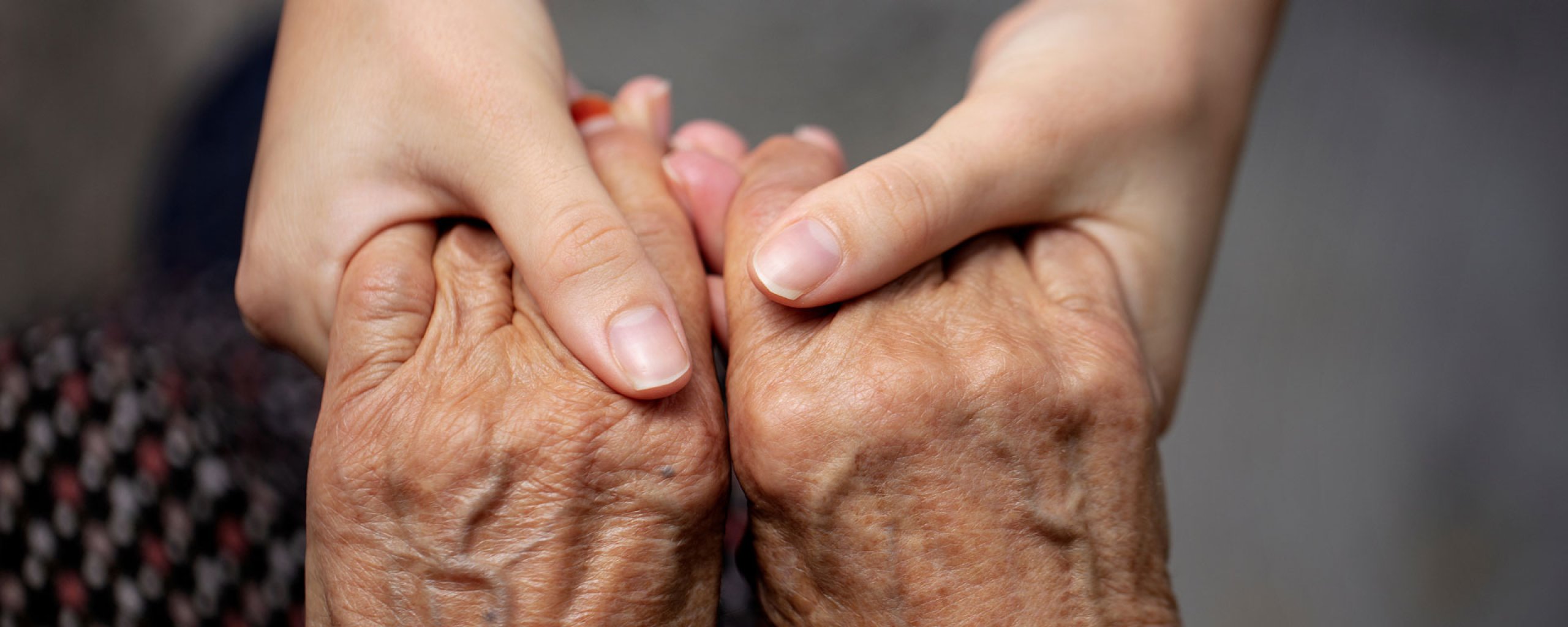 Foto van een paar jonge en een paar oude handen, die elkaar vasthouden