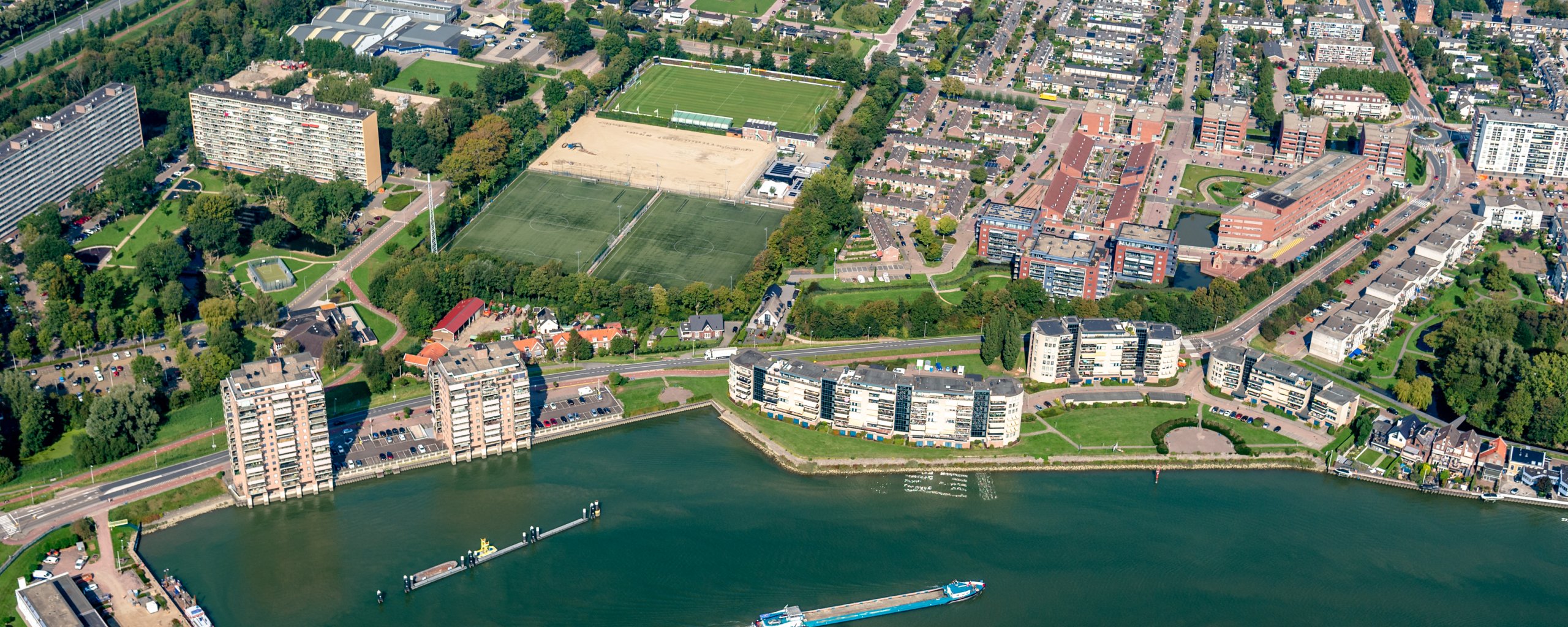 Luchtofoto van Capelle met de Hollandse IJssel op de voorgrond daarachter de Ketensedijk en de IJsselzoom de voetbalvelden en verpleeghuis Rozenburcht