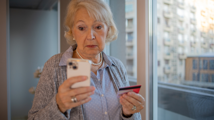 Vrouw met bankkaart en telefoon in haar hand