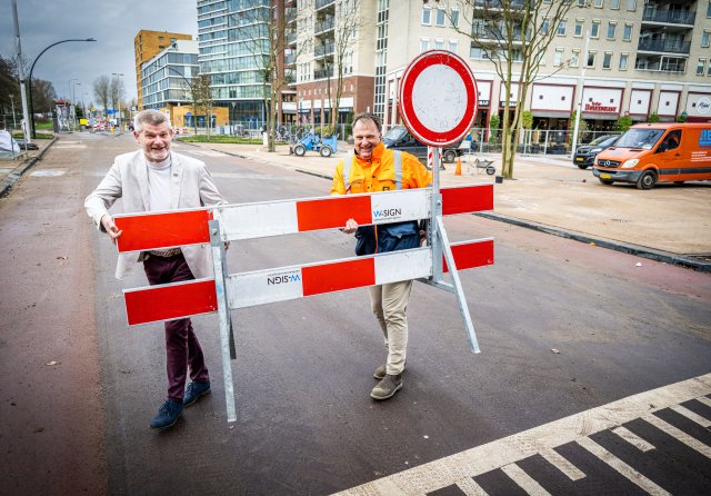 Wethouder Cor Schaatsbergen (links) haalt de hekken weg van de Rivierweg. De weg is weer open. Foto: Frank de Roo