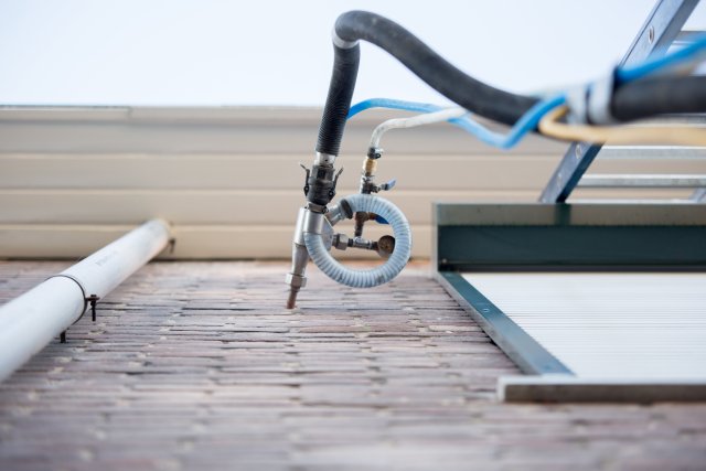 Boorinstallatie die isolatiemateriaal in een bakstenen gevel spuit voor spouwmuurisolatie.