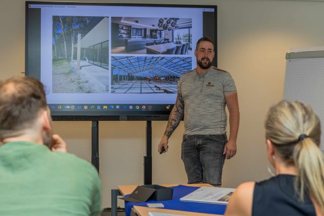een deelnemer houdt een presentatie voor een scherm