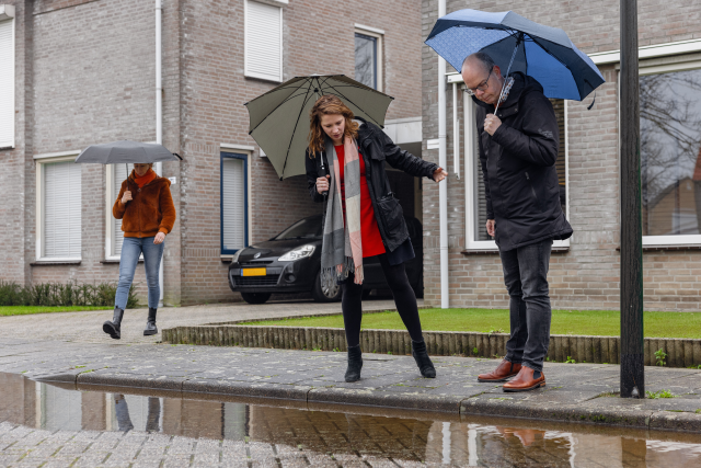 Een foto van twee mensen die kijken naar een verstopte straatkolk