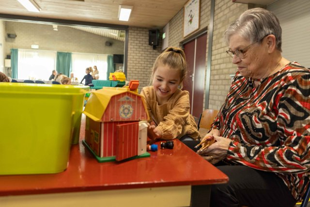 Spelend kind aan een tafel samen met een oudere dame