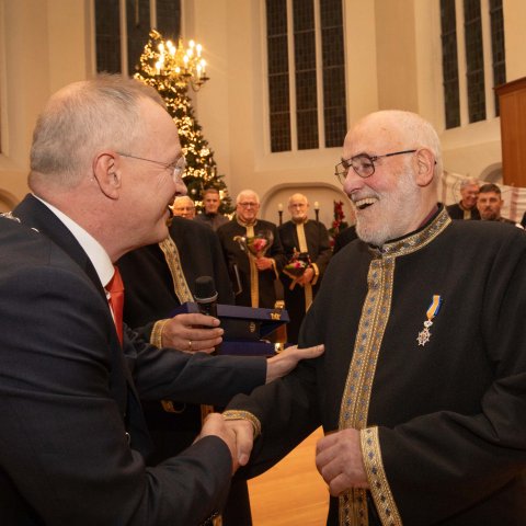 Burgemeester Michael Sijbom staat naast Ab Kleinlugtenbeld die hij feliciteert met de onderscheiding.