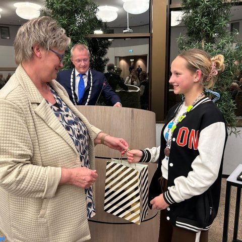 Raadslid Inge Haarman geeft kinderburgemeester Milou Groen een cadeau.