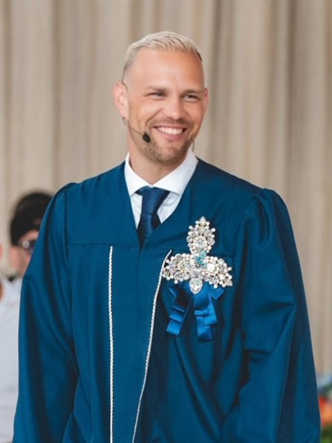 Niek Loman lachend in een blauwe toga