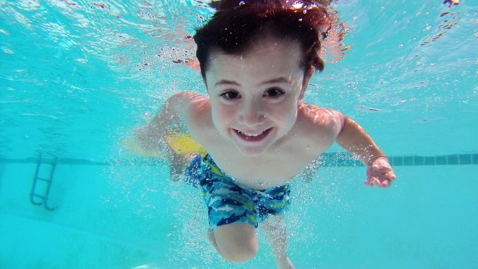 Onderwater zwemmend lachend jongetje in zwembad