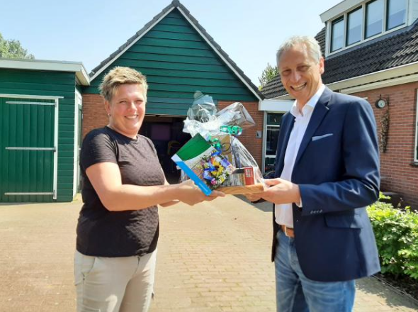 Wethouder Jan Uitslag feliciteert mevrouw Henriet Broer op de oprit van haar woning.