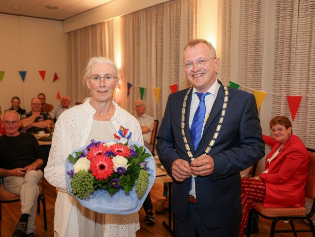 Op de foto staan Rebecca Feenstra met een bos bloemen en een lintje opgespeld en burgemeester Michael Sijbom.
