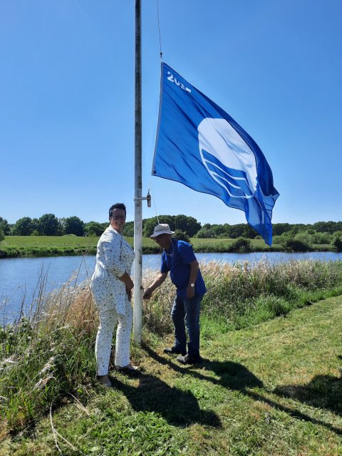 Wethouder Betsy Ramerman en havenmeester Haroet Baghdasarian hijsen de blauwe vlag.