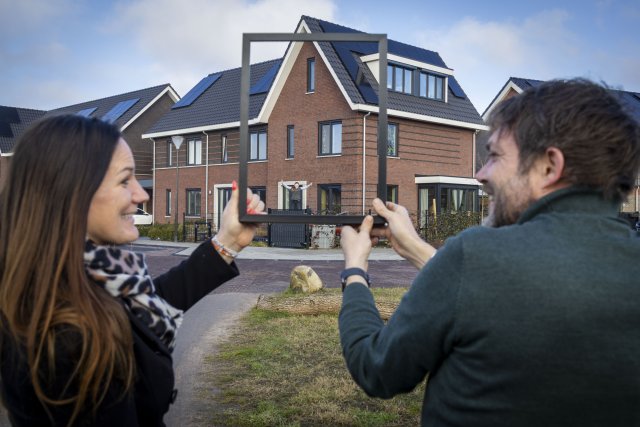 Op de foto Ronald Schoemaker en Gertrude Meijer die door een fotolijst kijken naar hun cpo-woning.