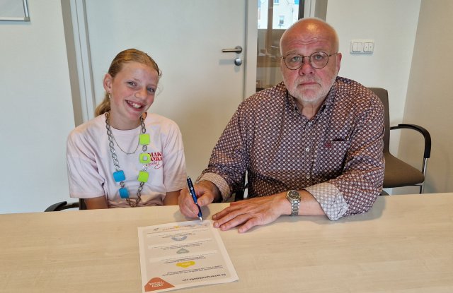 Kinderburgemeester Lela Dijsselhof met wethouder Ruud van Leeuwen. Ze tekenen de speelbelofte.