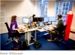 Meerde werknemers Kiesraad aan een bureau