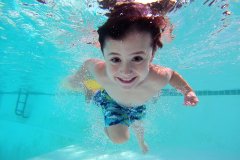 Afbeelding zwemmend kind onder water kijkend naar de camera