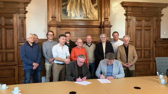 Foto van de ondertekenaars van de samenwerkingsovereenkomst: Sven Turnhout (Zorgboog), Jos vd Berkmortel (burgerinitiatief). Achter hen staan Marcel de Bakker (huisartsen de Poort), Dirk-Jan Willekens (Elkerliek), Mischa Kleukers (Prodas), Mark Kieft (Bergopwaarts), Marjan Vrijnsen-de Corte, wethouder, Jan vdr Steen en Gerrit vd Heuvel (beide seniorenkring Deurne/burgerinitiatief), Jac van Oppen (senioren Deurne centrum/burgerinitiatief), Ferd Raaymakers (ZorgboogExtra/burgerinitiatief), Thijs vd Nieuwenhof