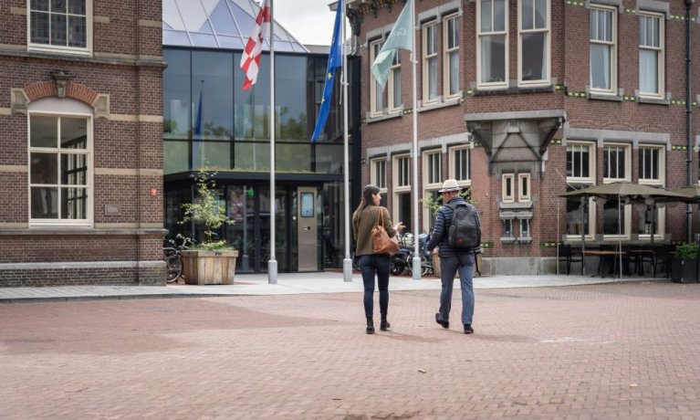 Twee medewerkers lopen gezellig kletsend naar het Huis voor de samenleving