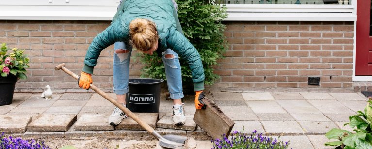 Een vrouw 'wipt' en stoeptegel en doet mee aan het NK Tegelwippen