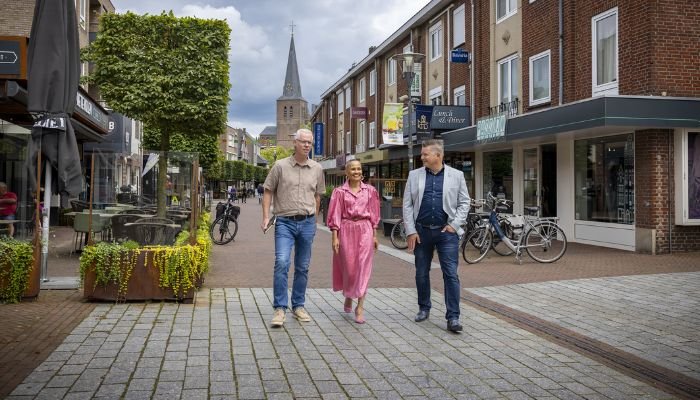 Drie personen wandelen door het gezellige centrum van Deurne.