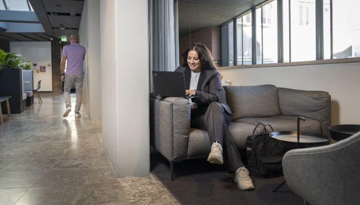 Een medewerker zit te werken op een laptop in een gemakkelijk zitje.
