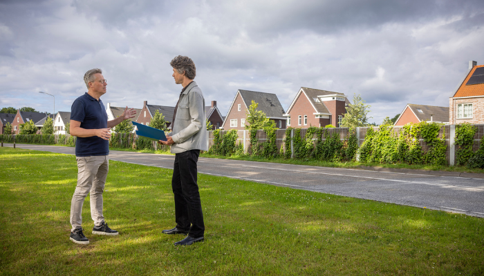 Twee personen zijn in gesprek over de wijk die op de foto te zien is.