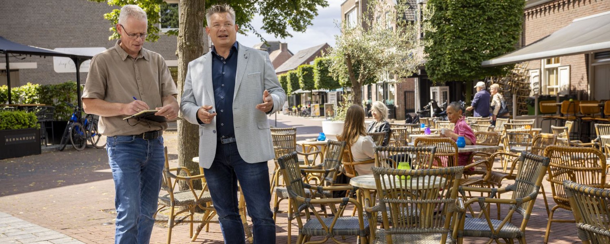 Twee personen in gesprek bij een gezellig terras in het centrum van Deurne.