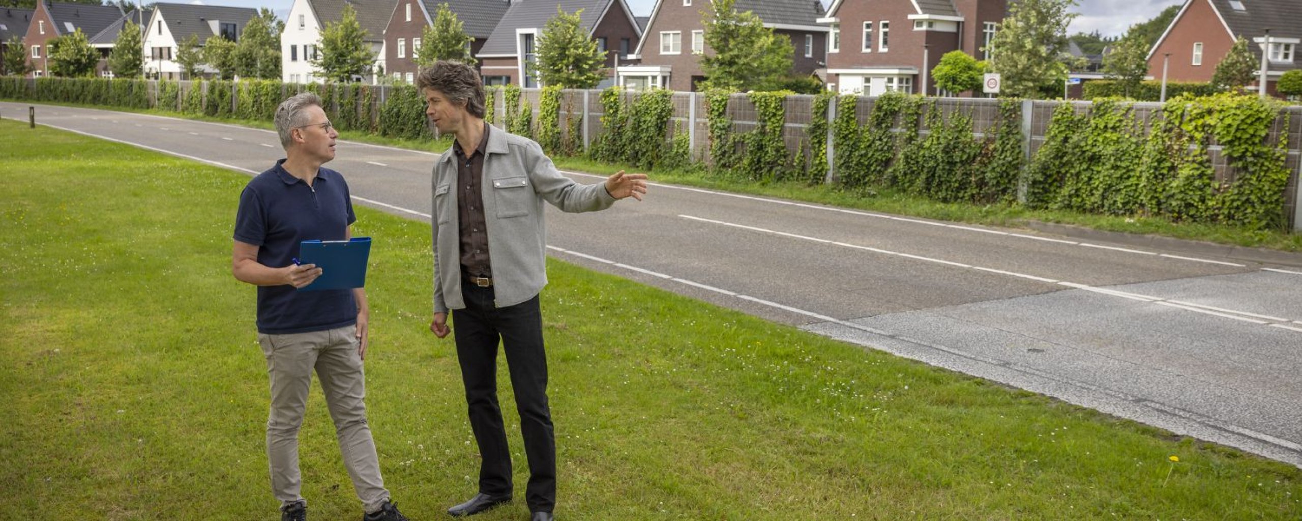 Twee personen zijn in gesprek met een aantal mooie huizen op de achtergrond