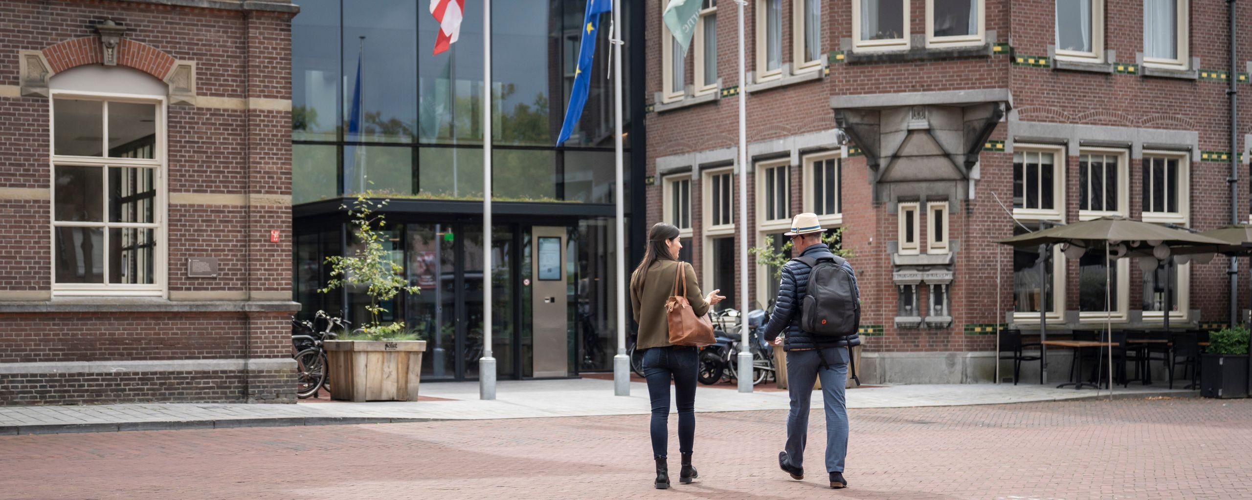 Vacature regisseur openbare ruimte, foto van 2 medewerkers wandelend naar het Huis voor de samenling Deurne