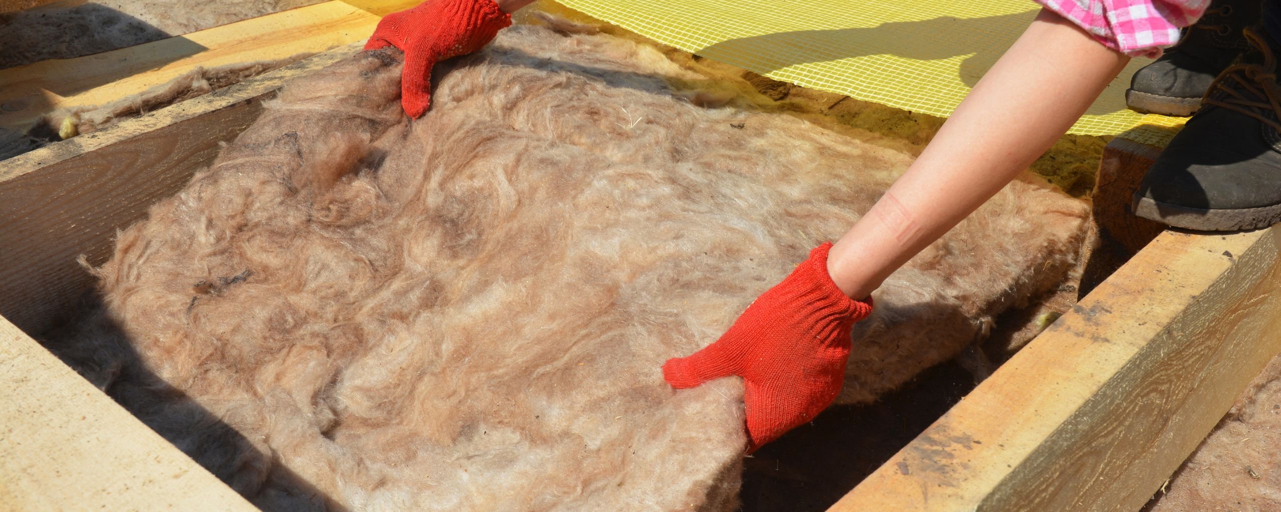 Foto van de handen van een persoon die isolatiemateriaal neerlegt.