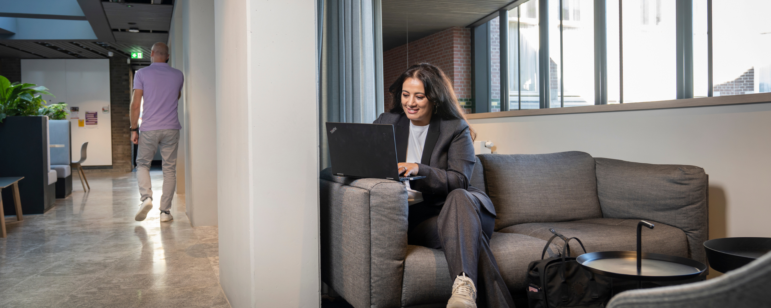 Een medewerker is aan het werk achter haar laptop in de ontmoetingsruimte.