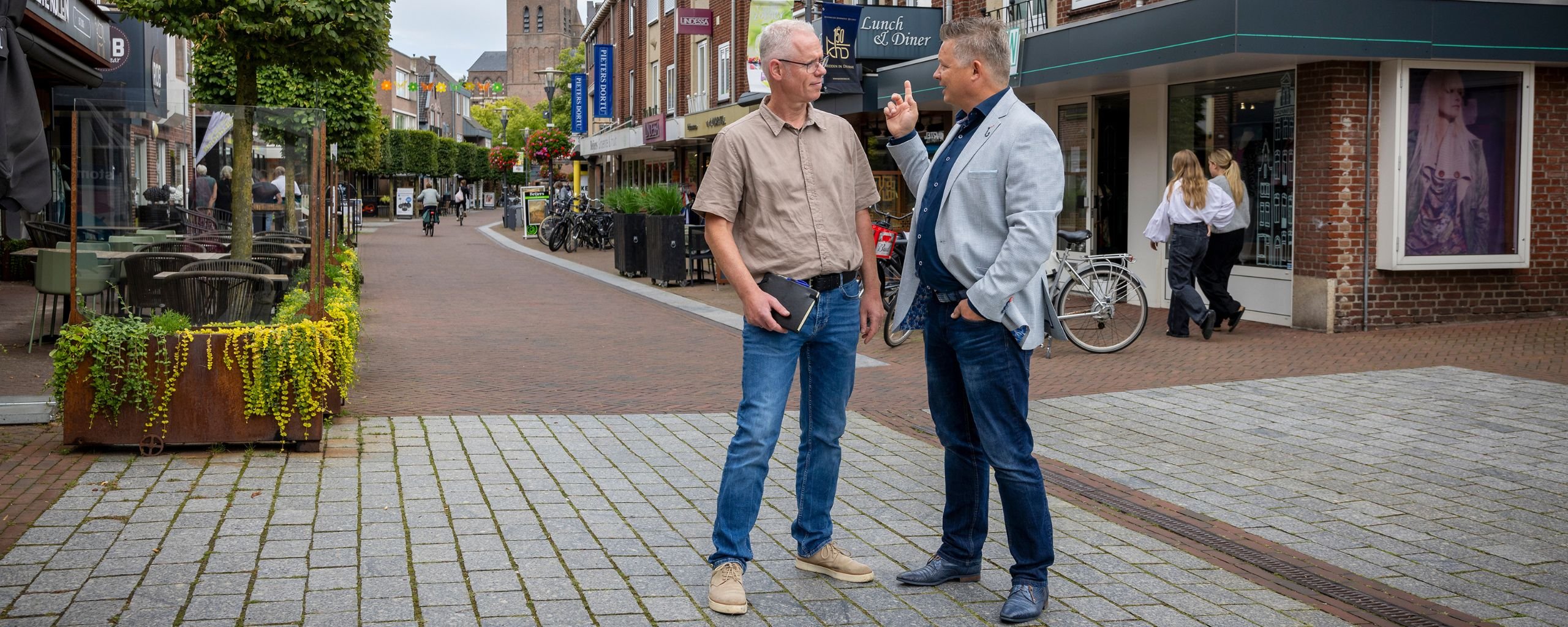 De twee medewerkers staan in het centrum van Deurne en zijn met elkaar in gesprek.