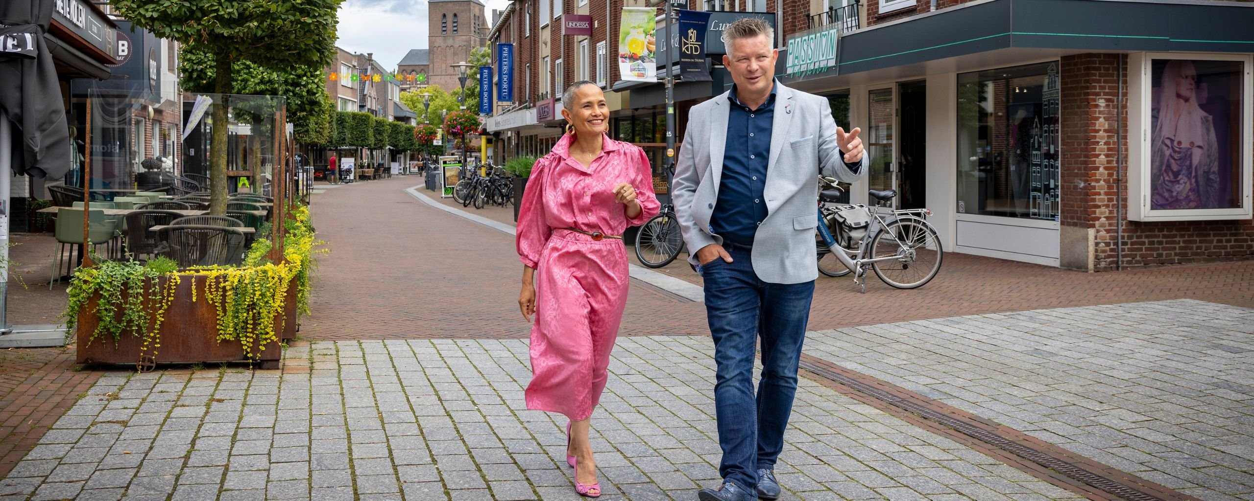 Twee medewerkers lopen samen door een straat in het centrum van Deurne.